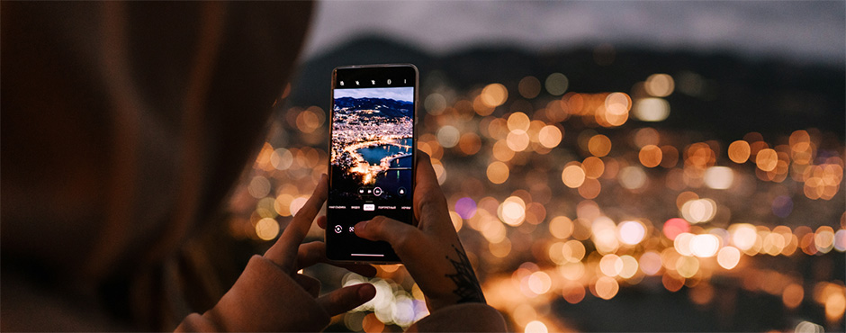 woman taking night photo of city with her phone