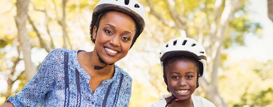 Mother and child wearing bicycle helmets and smiling